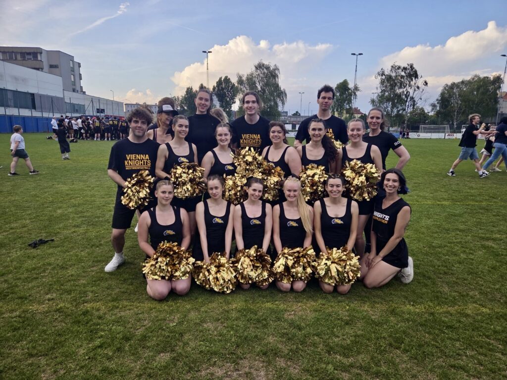 Cheerleading Team mit Gold Poms am Footballfeld